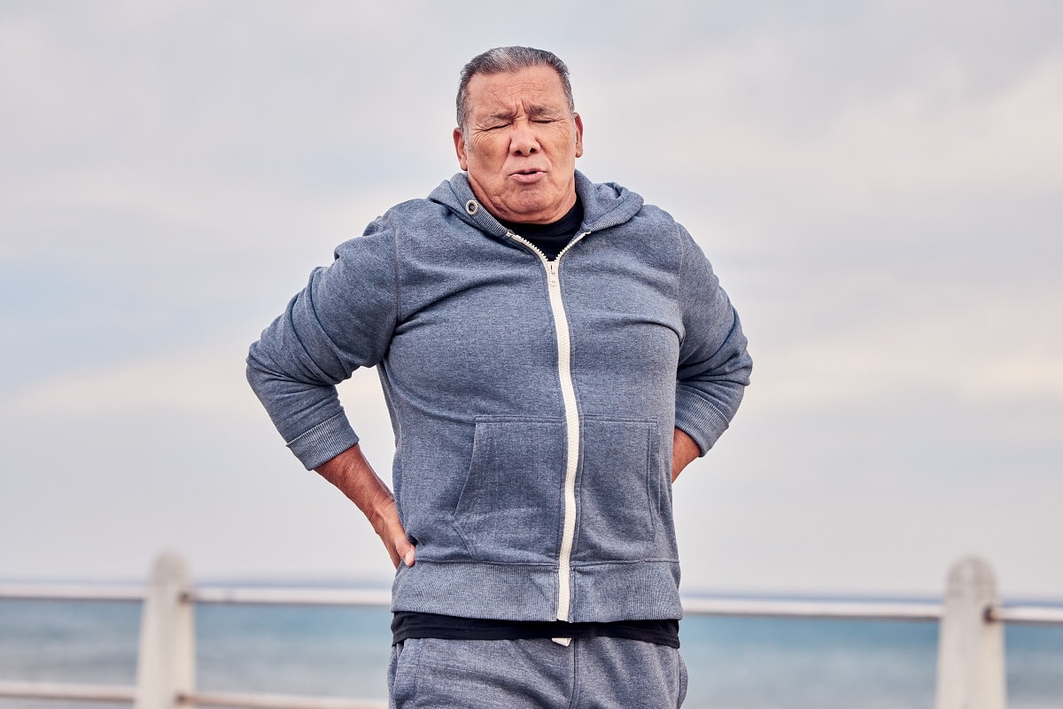 elderly back pain with scoliosis at beach