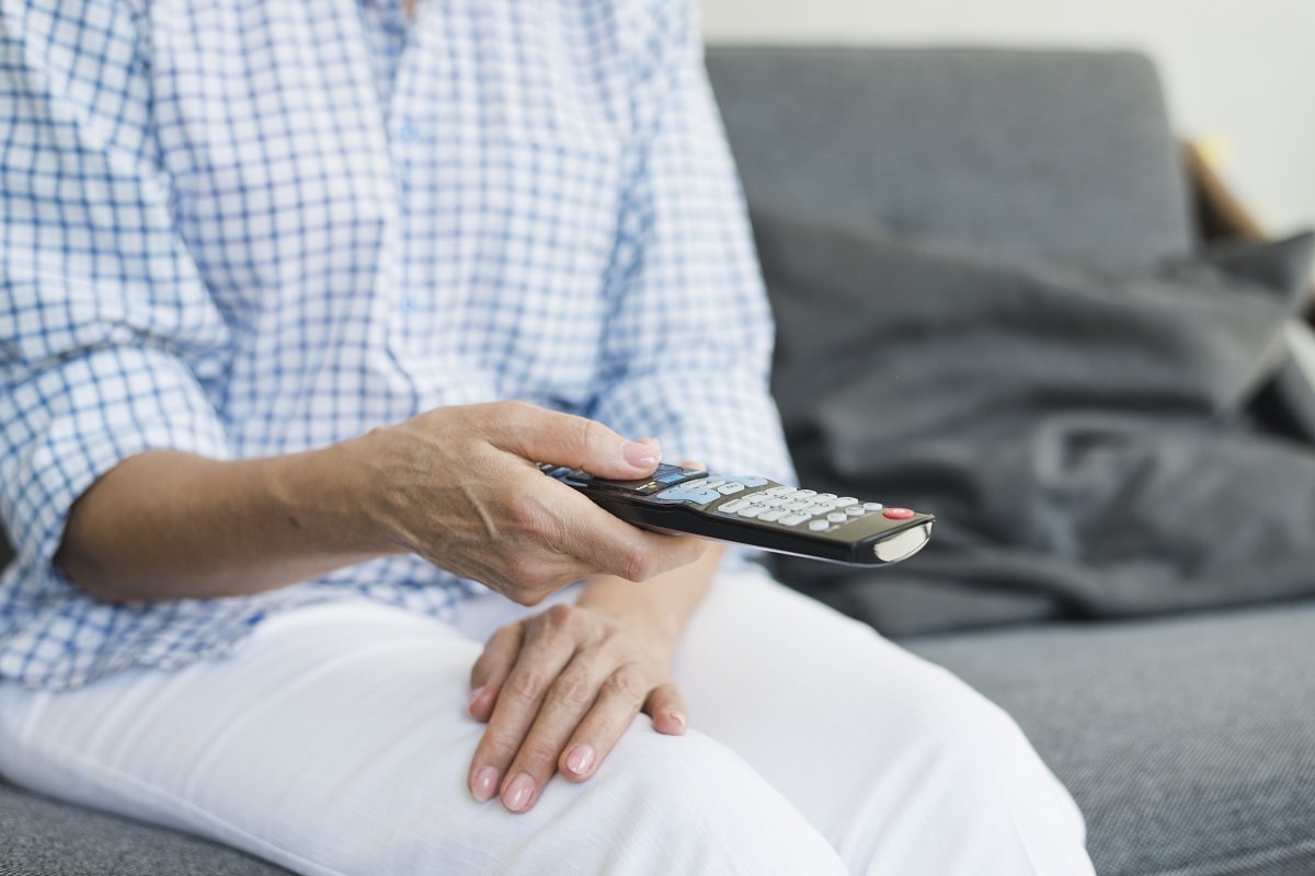 senior woman's hand holding tv remote control